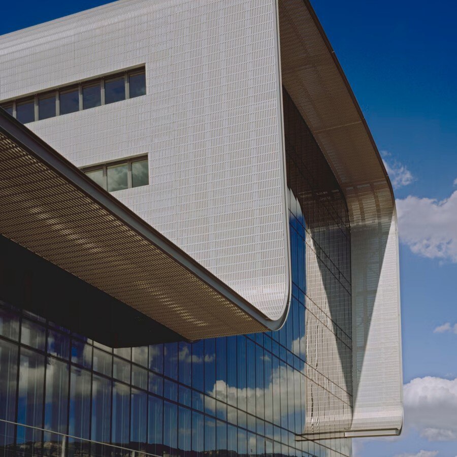 Exterior view of a modern building with sharp architectural lines and large glass windows, set against a clear blue sky.