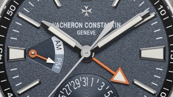 Vacheron Constantin watch dial with luminous hands and orange accents.