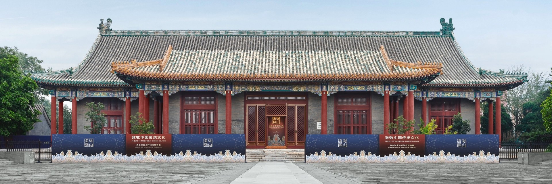 Front view of a traditional Chinese building with ornate roof details and red columns, captured under a clear blue sky.