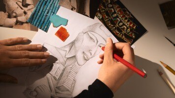 一隻手在白紙上繪製雅典娜的頭像。