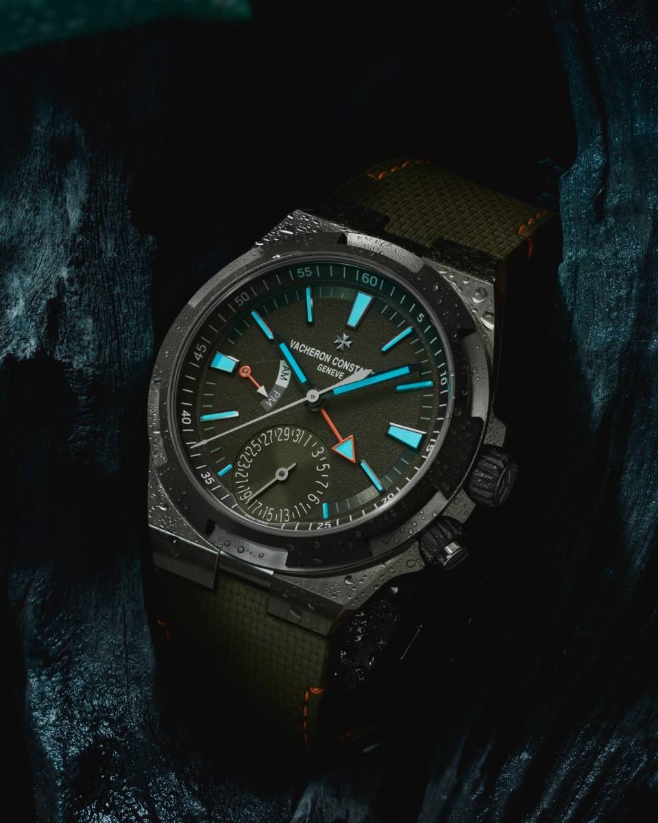 Green Overseas Dual Time Cardinal Points watch on a green, rocky background