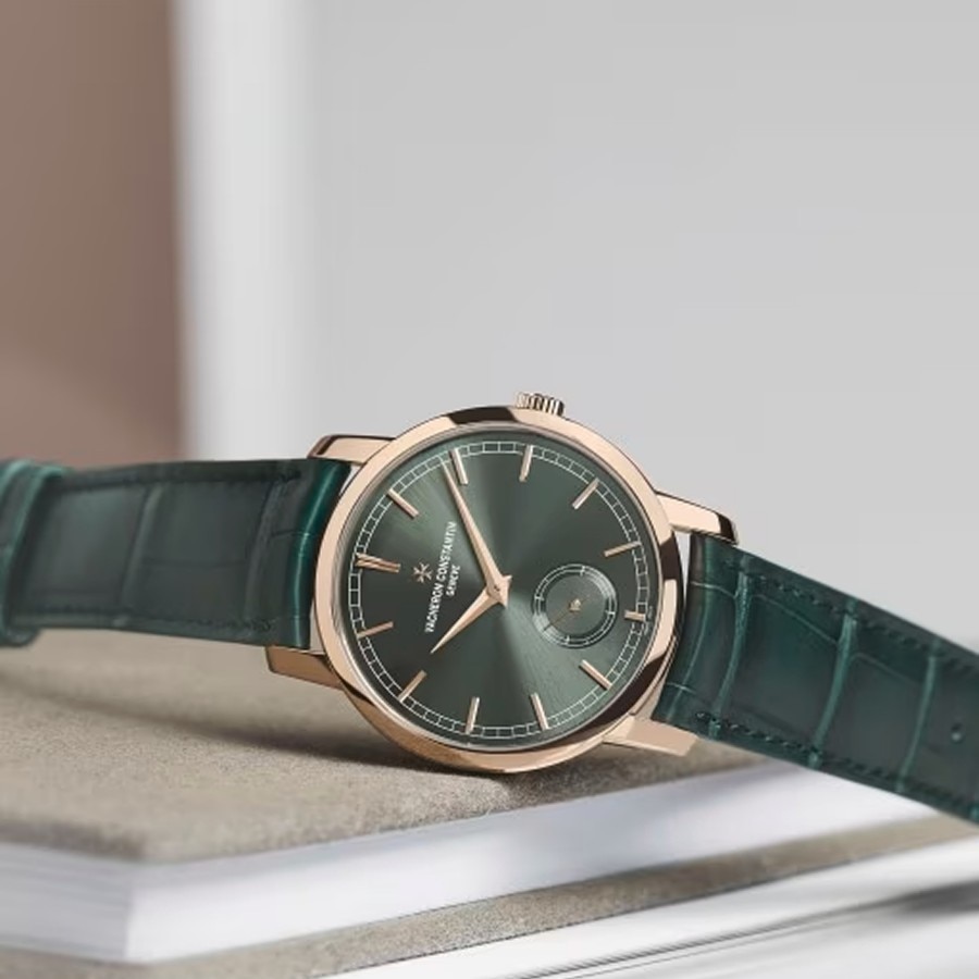 Finished green dial wristwatch with a green leather strap resting on a closed book.