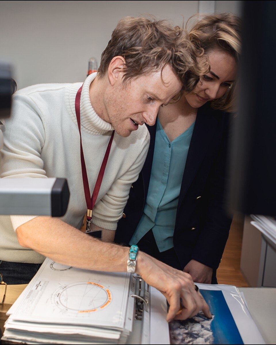 Two people looking at a screen, one wearing a medal.