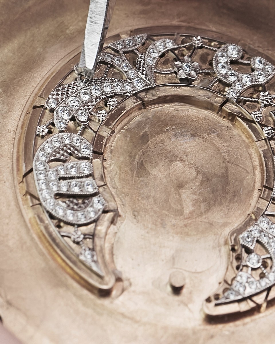 Detailed floral and ornamental diamond setting on a golden watch or jewelry component.