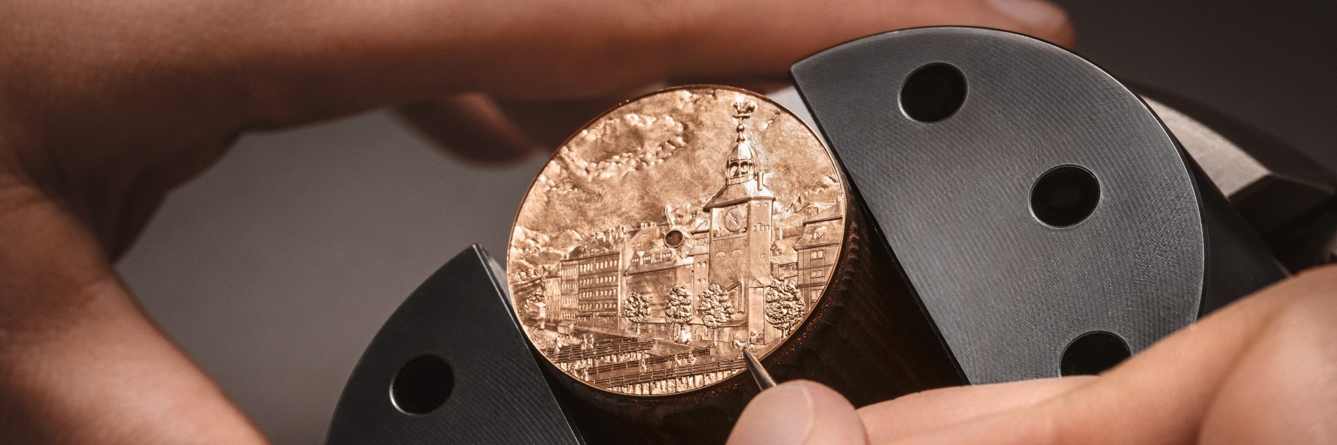 Hand engraving a detailed architectural scene on a round watch dial.