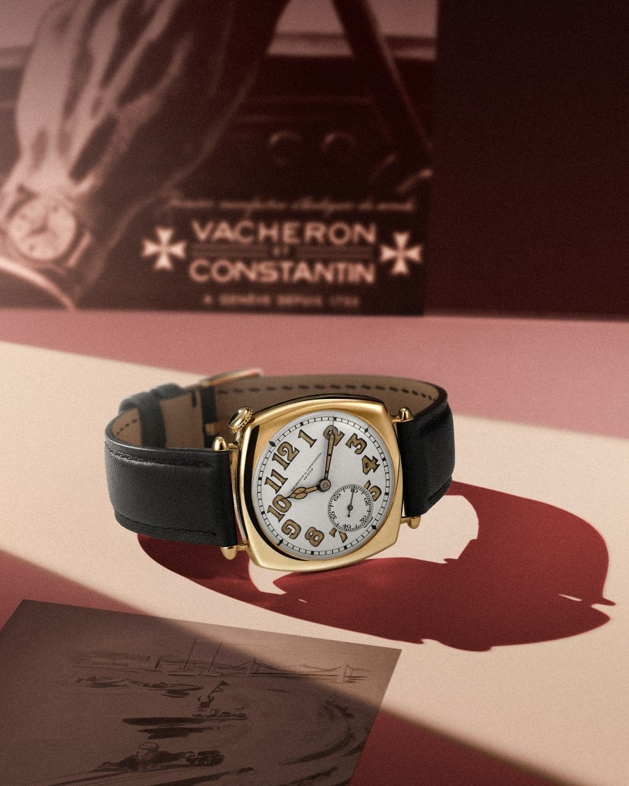 American 21 yellow gold watch on a table next to a Vacheron Constantin book