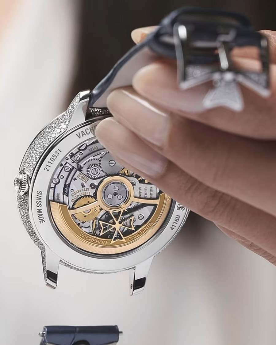 Detailed view of a watchmaker holding a Vacheron Constantin watch with an open case back, showcasing the mechanical movement.