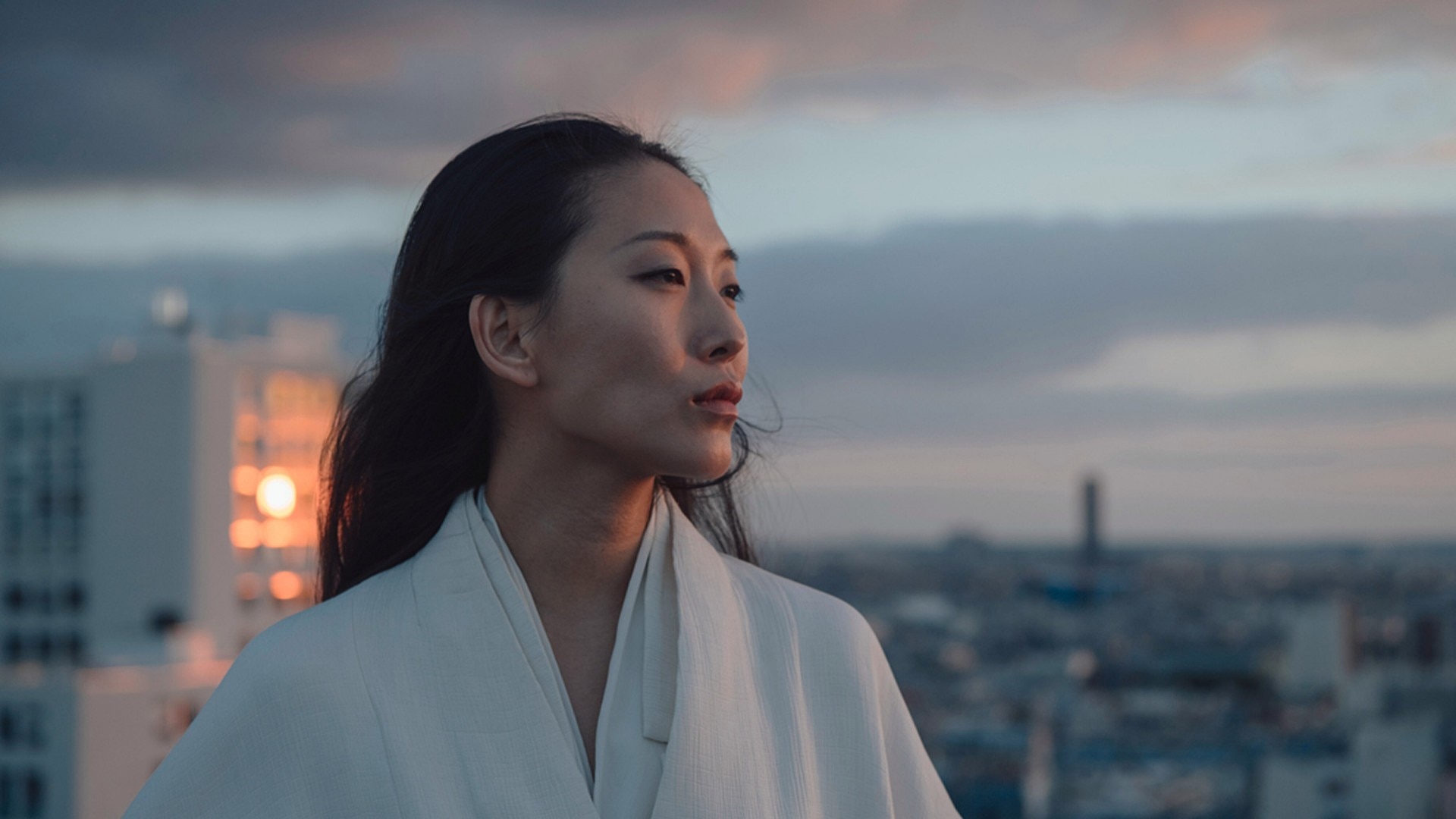 黄昏时分的一位女子的肖像,背景是城市景观。