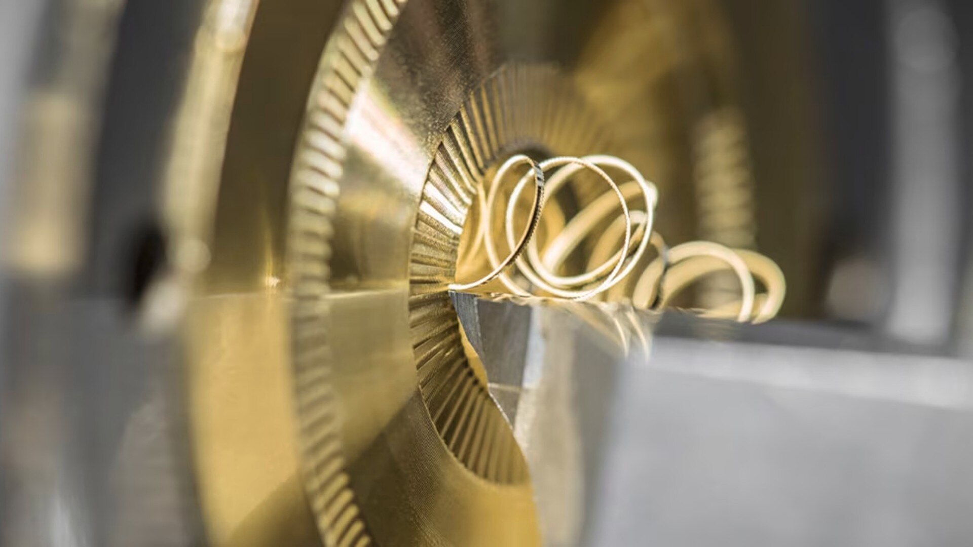 Detailed view of a watch gear being finely machined, with metal shavings curling off the surface.