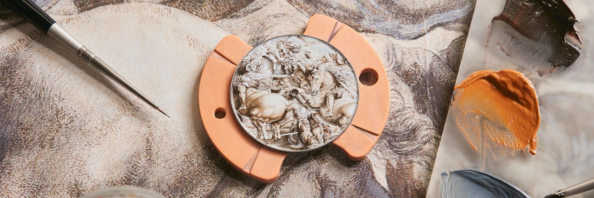 Close-up of an intricate enamelled watch dial with classic figures, surrounded by artisan tools.