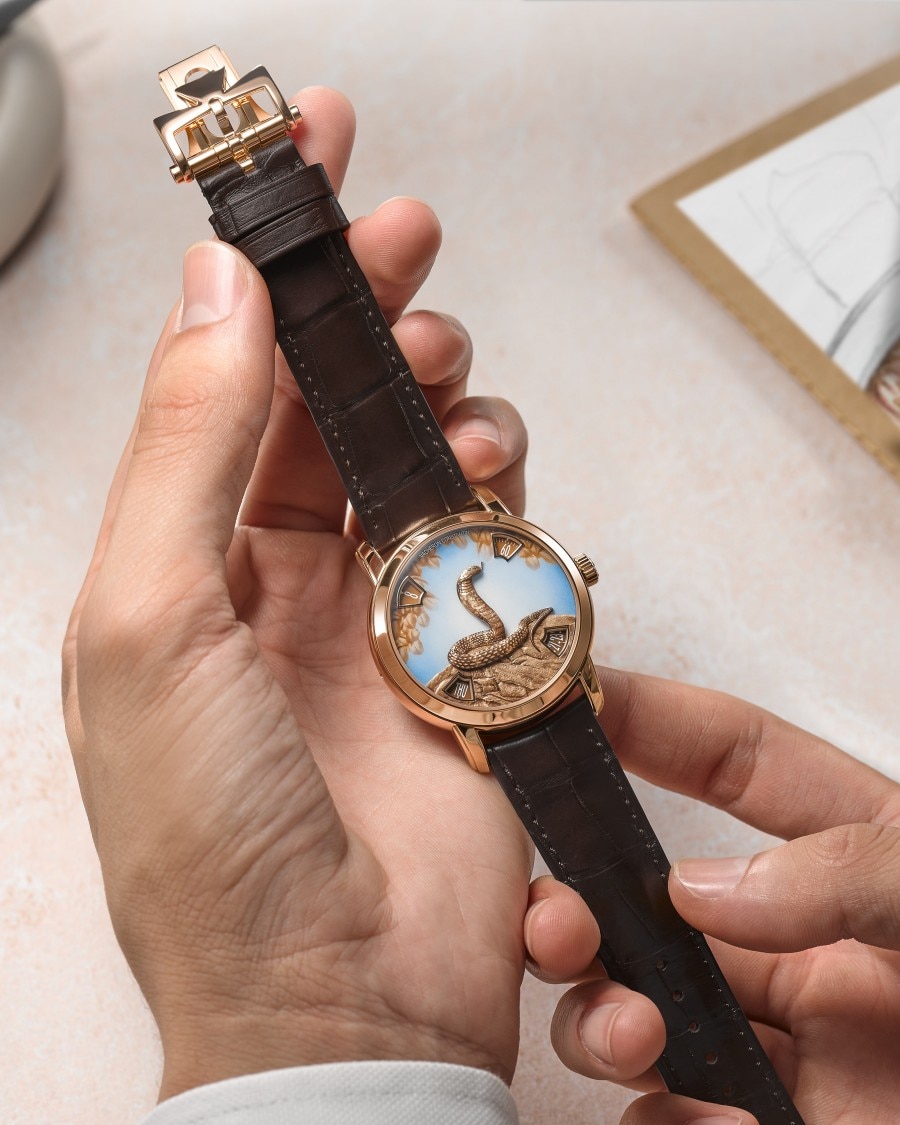 Métiers d’Art watch with artistic dial held by hand in white cuff.