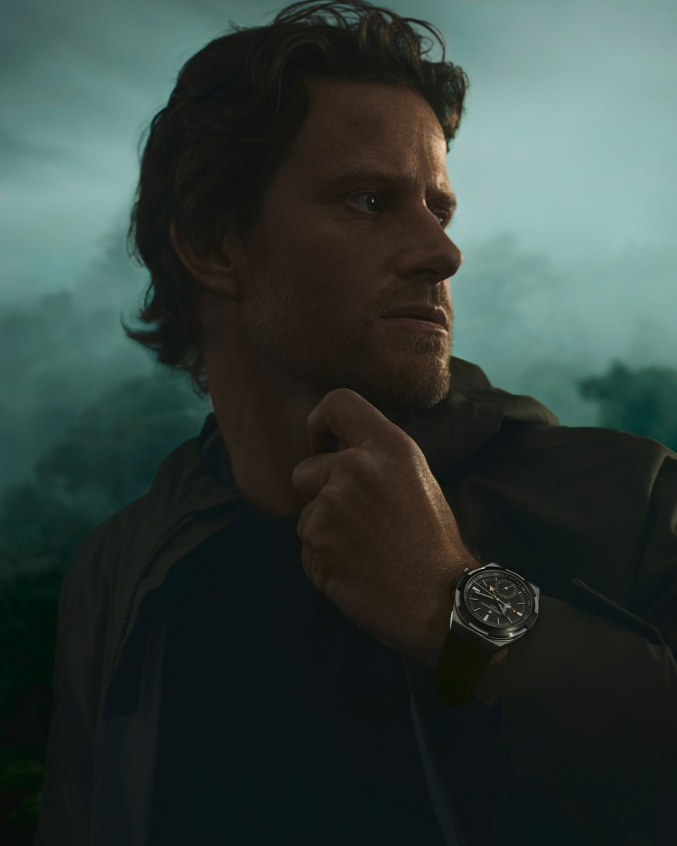 Cory Richards wearing the green Overseas Dual Time Cardinal Points watch with a forest background
