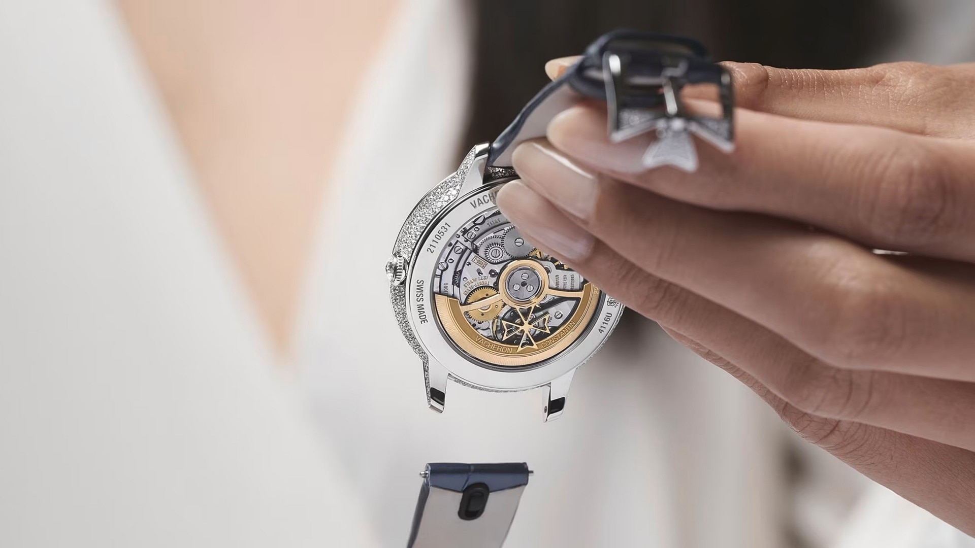 Detailed view of a watchmaker holding a Vacheron Constantin watch with an open case back, showcasing the mechanical movement.