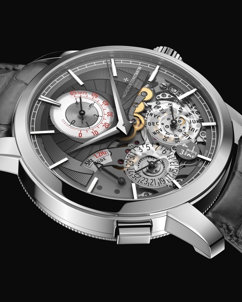 A luxury timepiece captured up close, highlighting its dark grey dial, open mechanics, and dark leather strap.