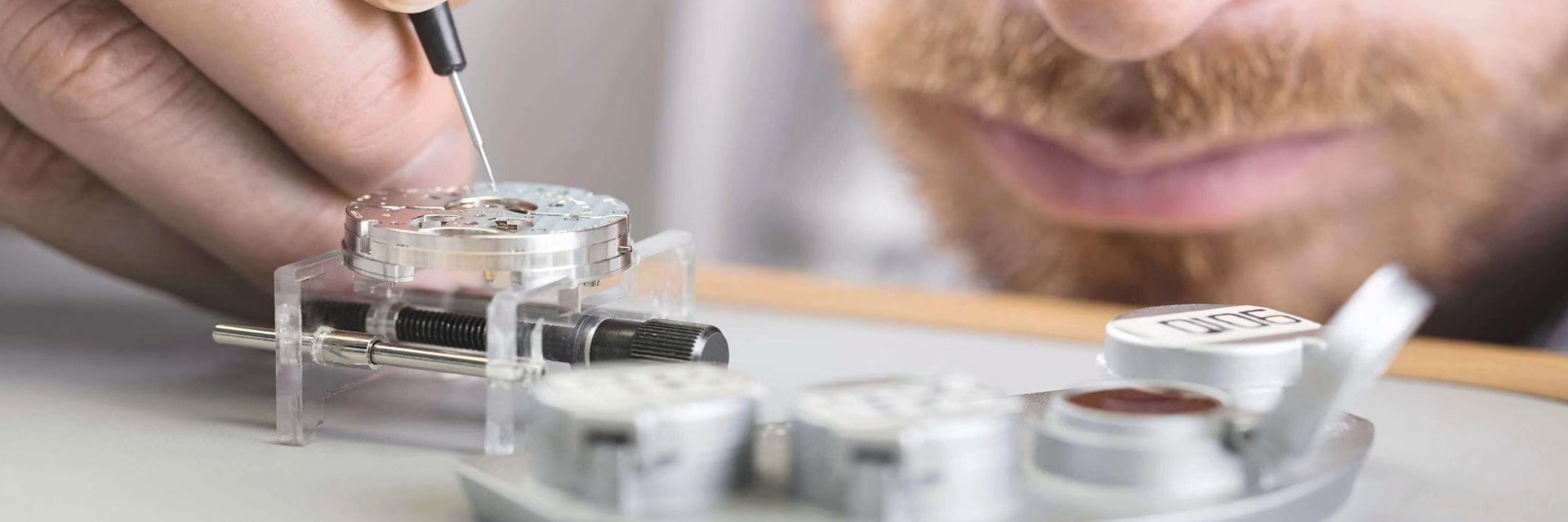 Watchmaker performing a precise assembly of a watch movement under magnification.