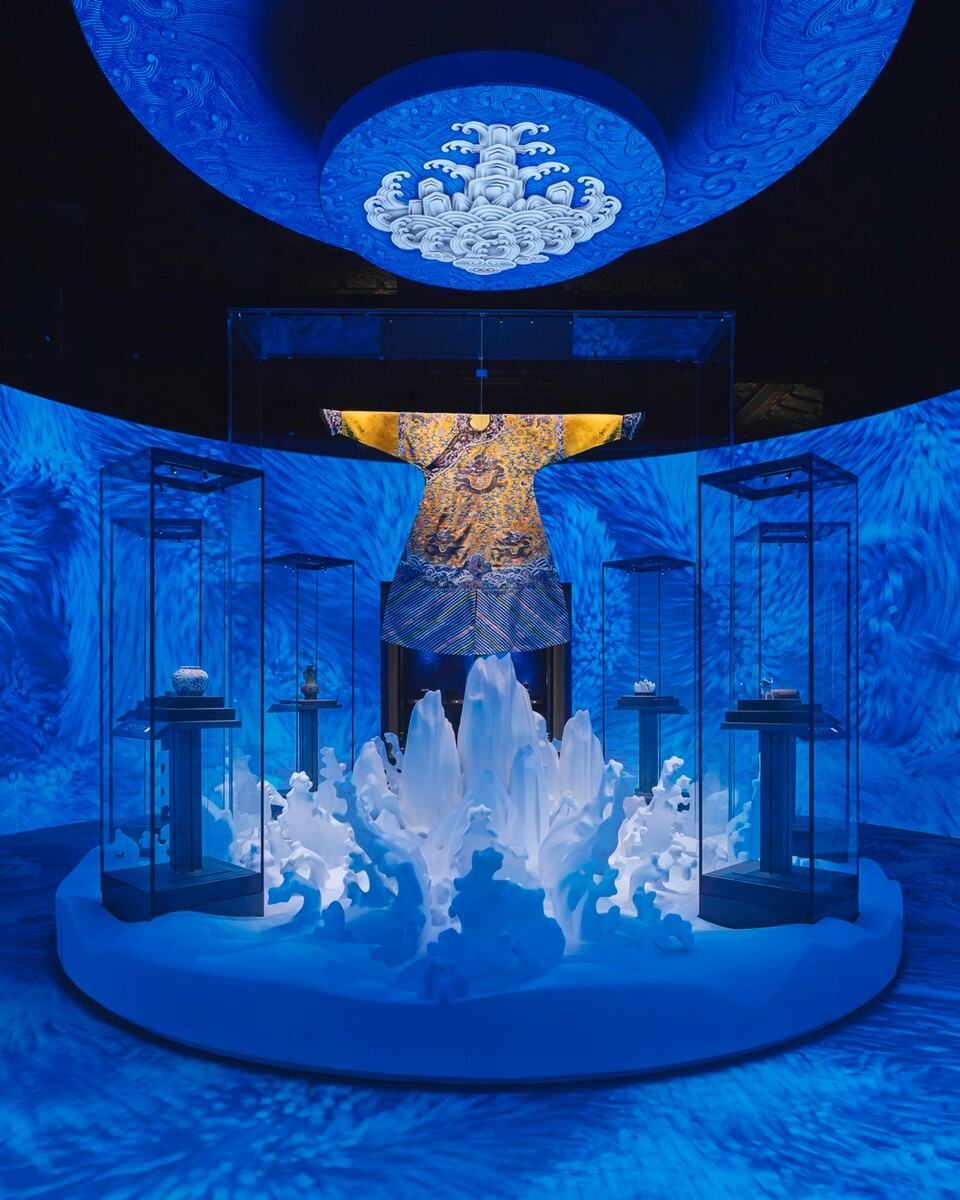Blue-lit museum exhibition featuring crystal sculptures and digital art displays.