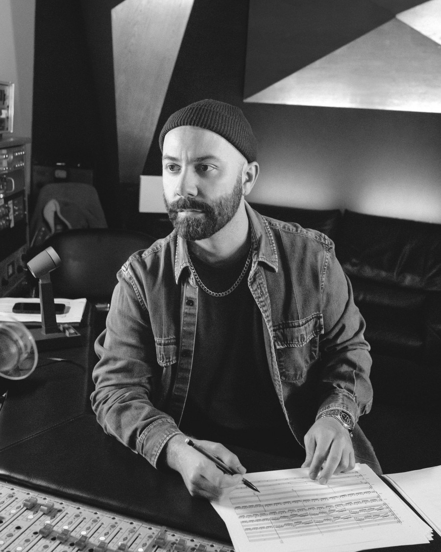 Woodkid in a studio, reviewing sheet music.
