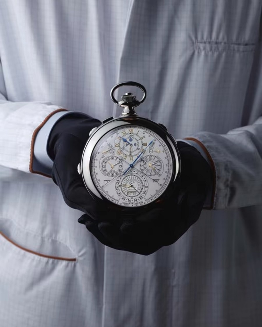Gloved hands holding a vintage  pocket watch against a white lab coat.