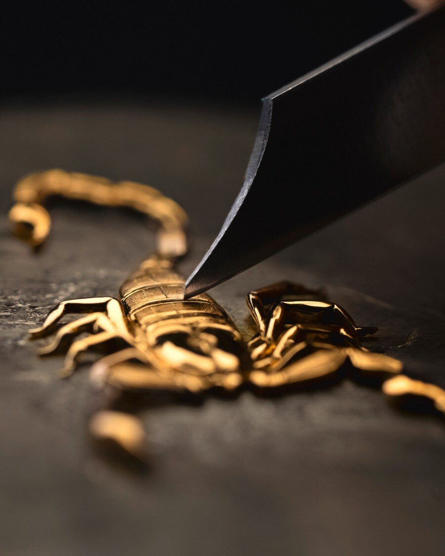 High-relief engraving Image illustarting a golden scorpion hit by a tool