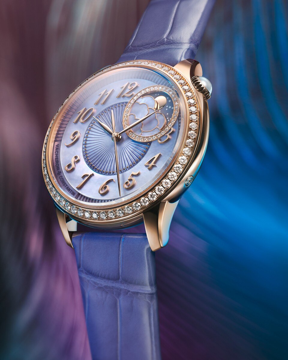 Close-up of a luxury wristwatch with a moonphase and star motif against a rich blue background.