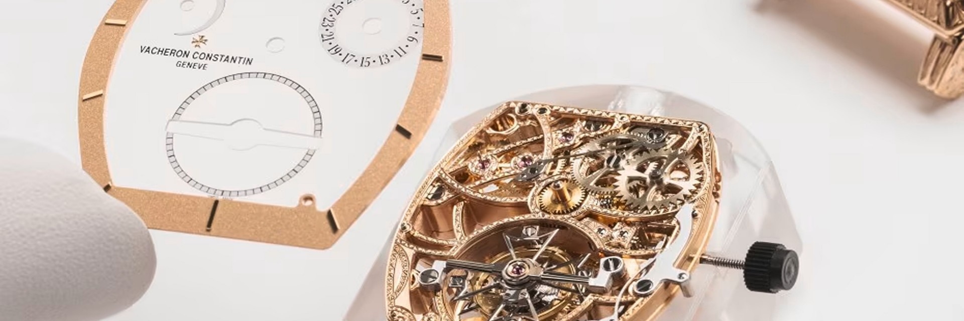 Skeleton watch movement with gold bazel and dial parts on a white surface.