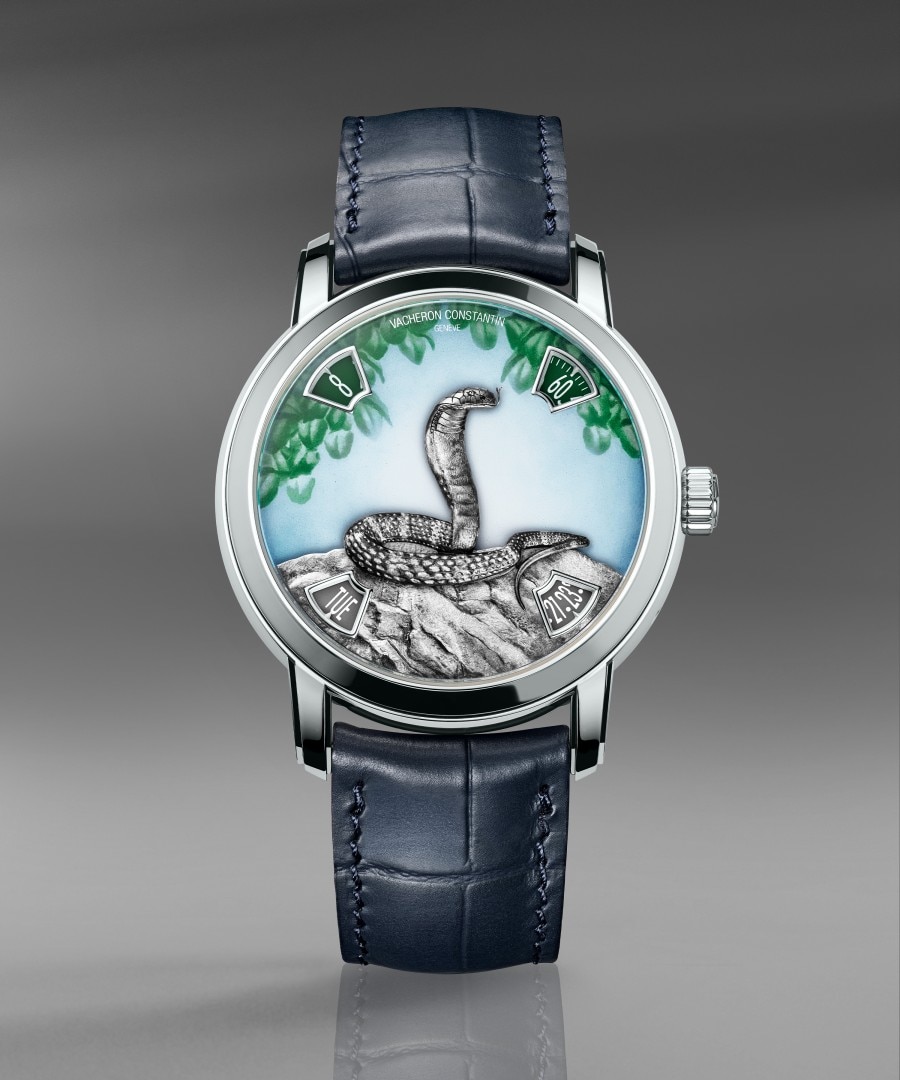 Métiers d'Art The legend of the Chinese zodiac - year of the snake Luxury watch with a hand-painted dial depiciting a snake surrounded by green leaf details, paired with a dark blue leather strap.