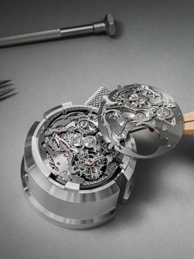 Intricate watch movement being assembled, showcasing gears and decorative skeletonized components.