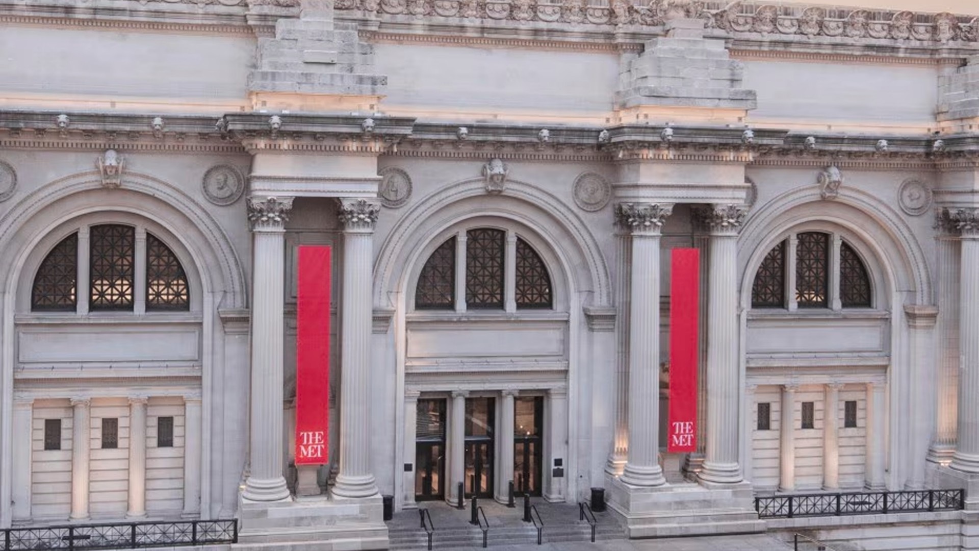 Front entrance of  The Met with red banners and classical architecture.