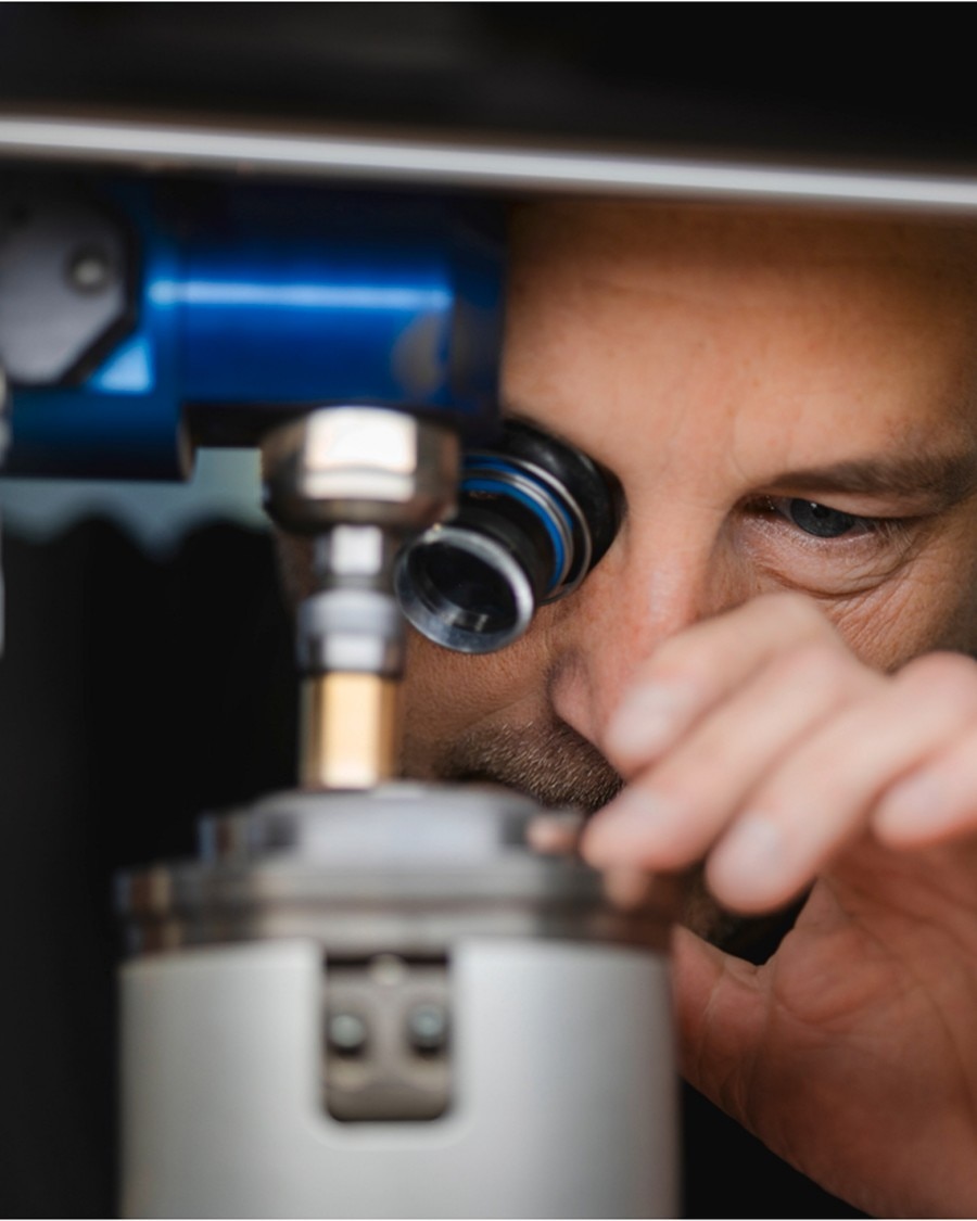 Watchmaker examining a component through a microscope.