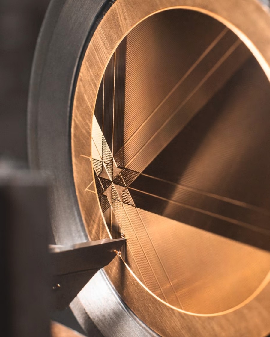 Engraving process on a gold watch dial with intricate geometric patterns.