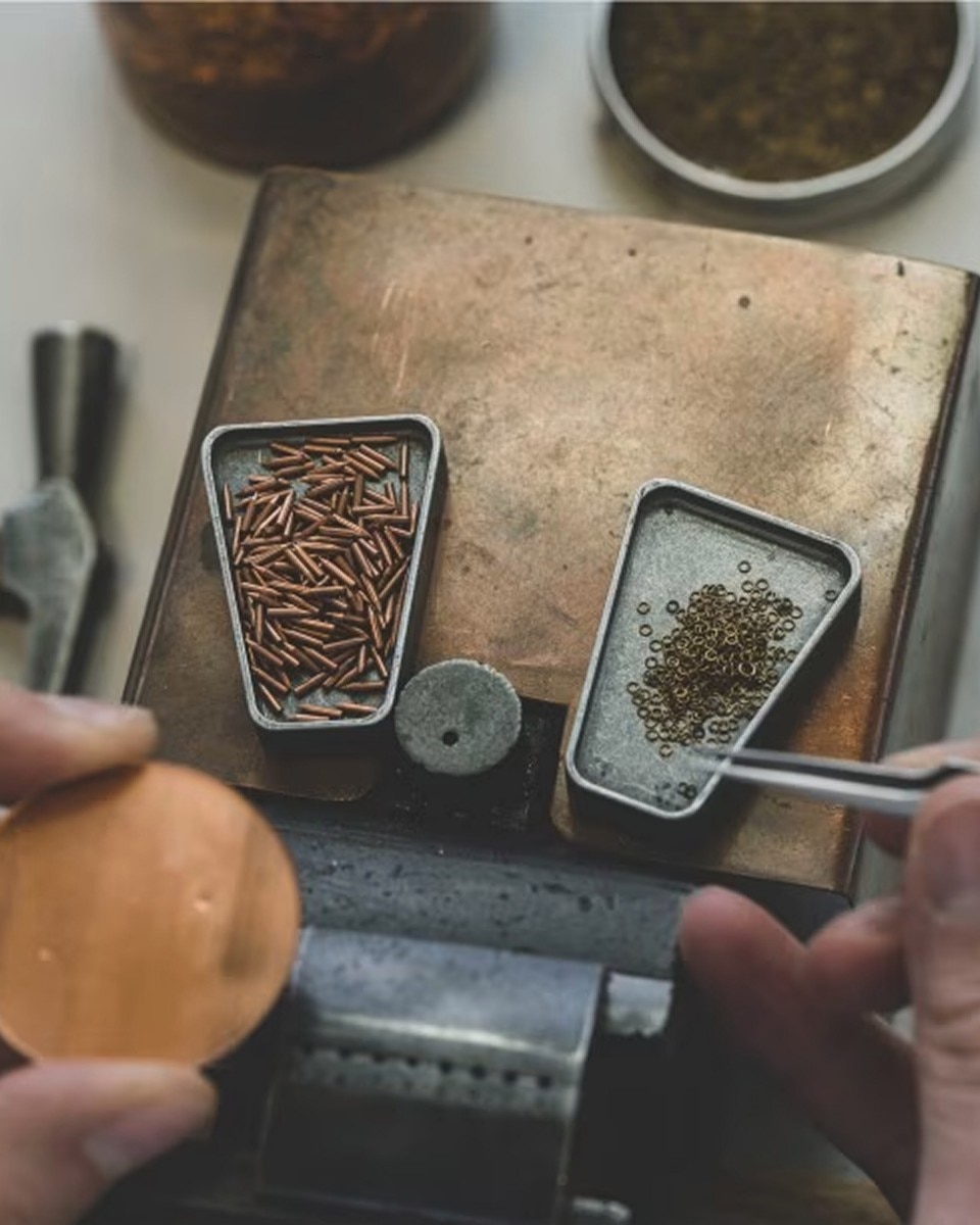 Artisan's workspace with small containers holding watch parts and tools.