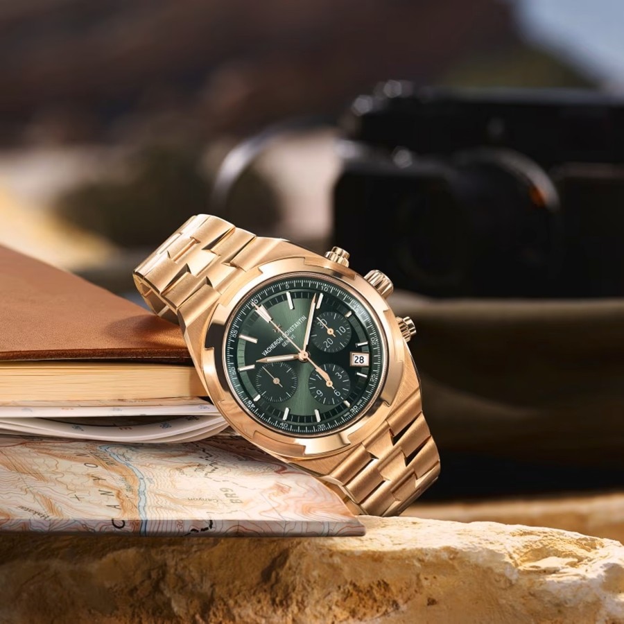 Vacheron Constantin chronograpgh in gold with a green dial, placed on a textured surface.