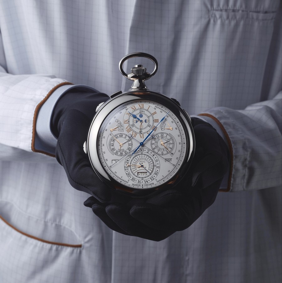 双手托起一枚具备复杂计时细节的大型钟表表头。