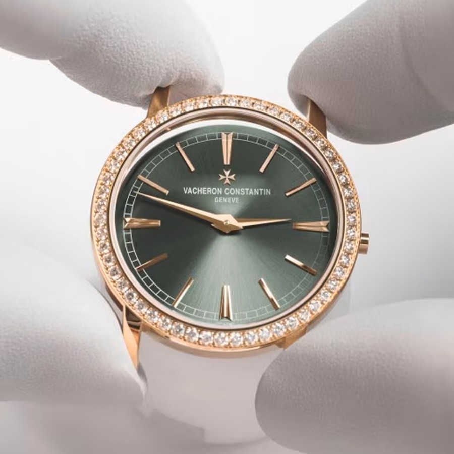 Green dial luxury watch with a gold case and diamond bezel, displayed upright.
