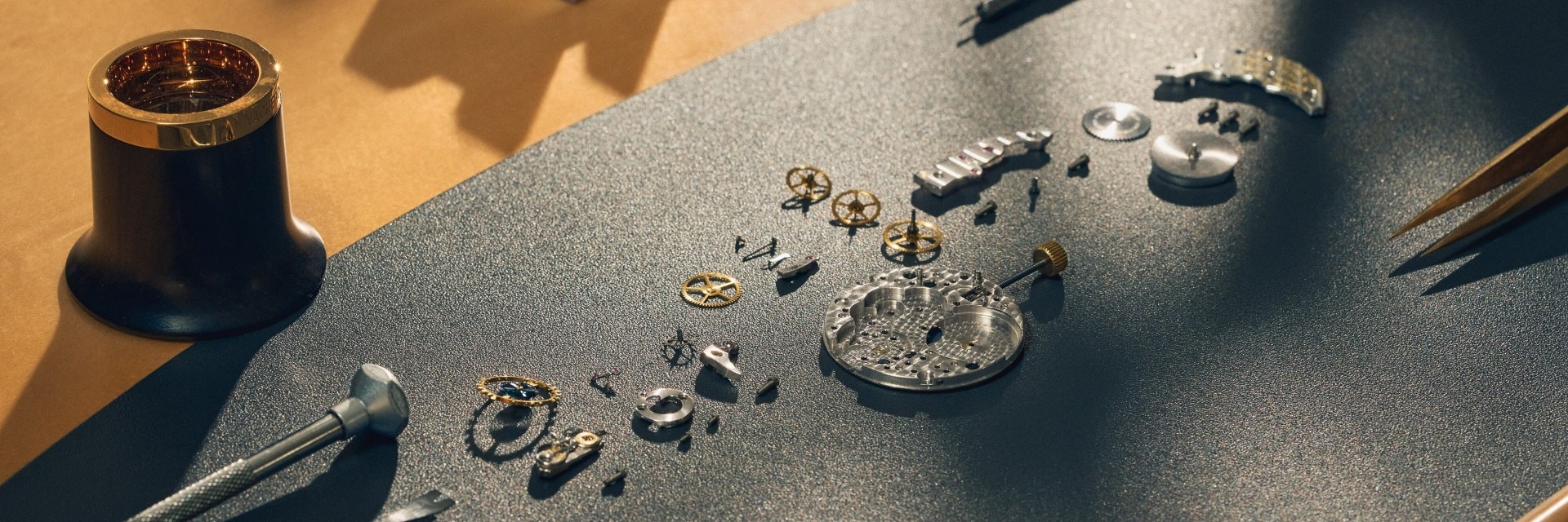 A hand with tweezers places the mechanism on the open watch case