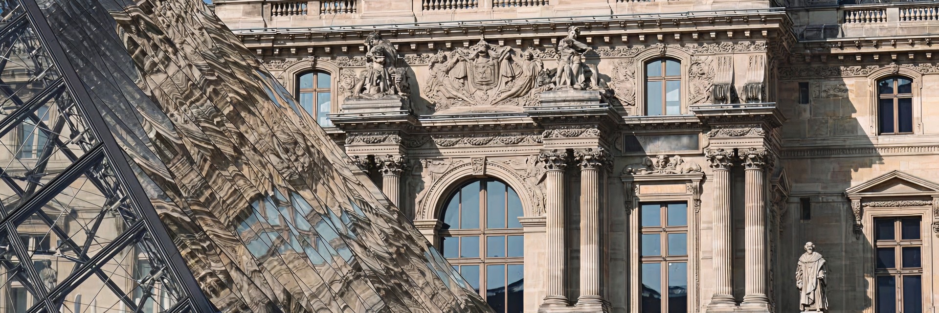View of the Louvre Museum façade with the glass pyramid in front.
