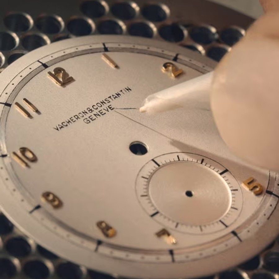 Close-up of a vintage-style watch dial with visible hour markers and disassembled components.