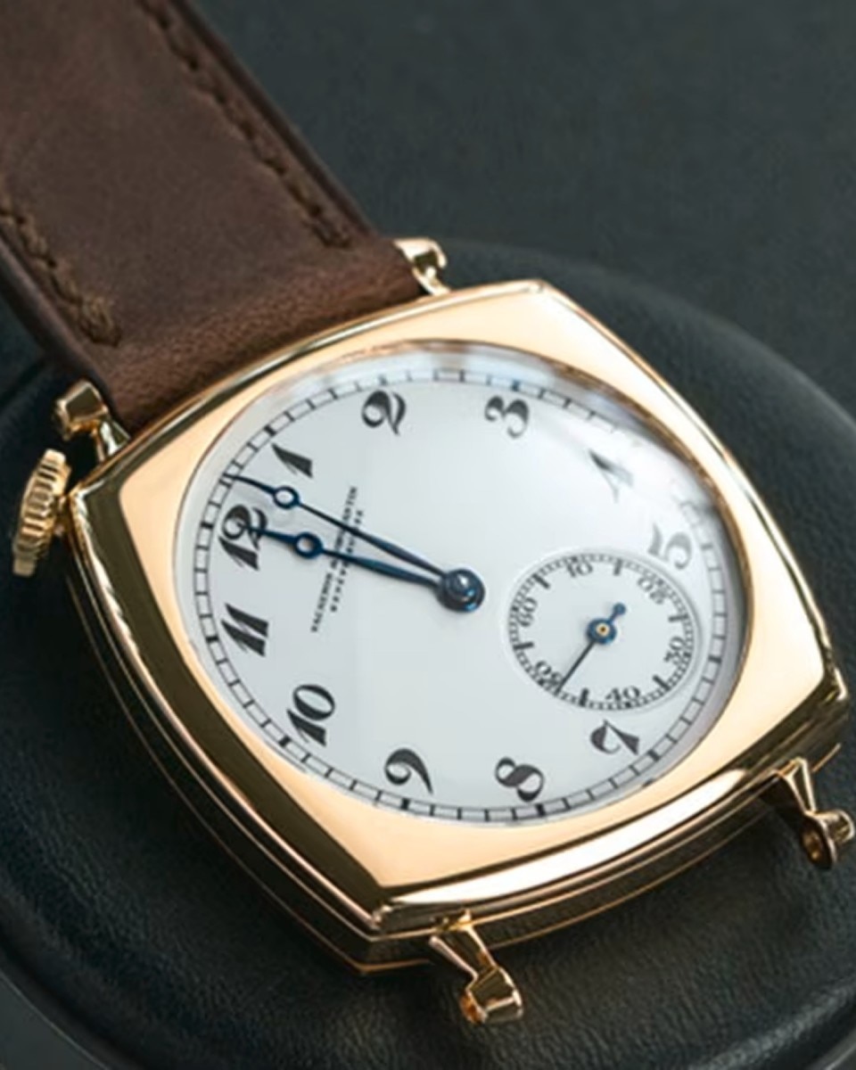 Close-up of a vintage Vacheron Constantin watch with a white dial and  brown leather strap.