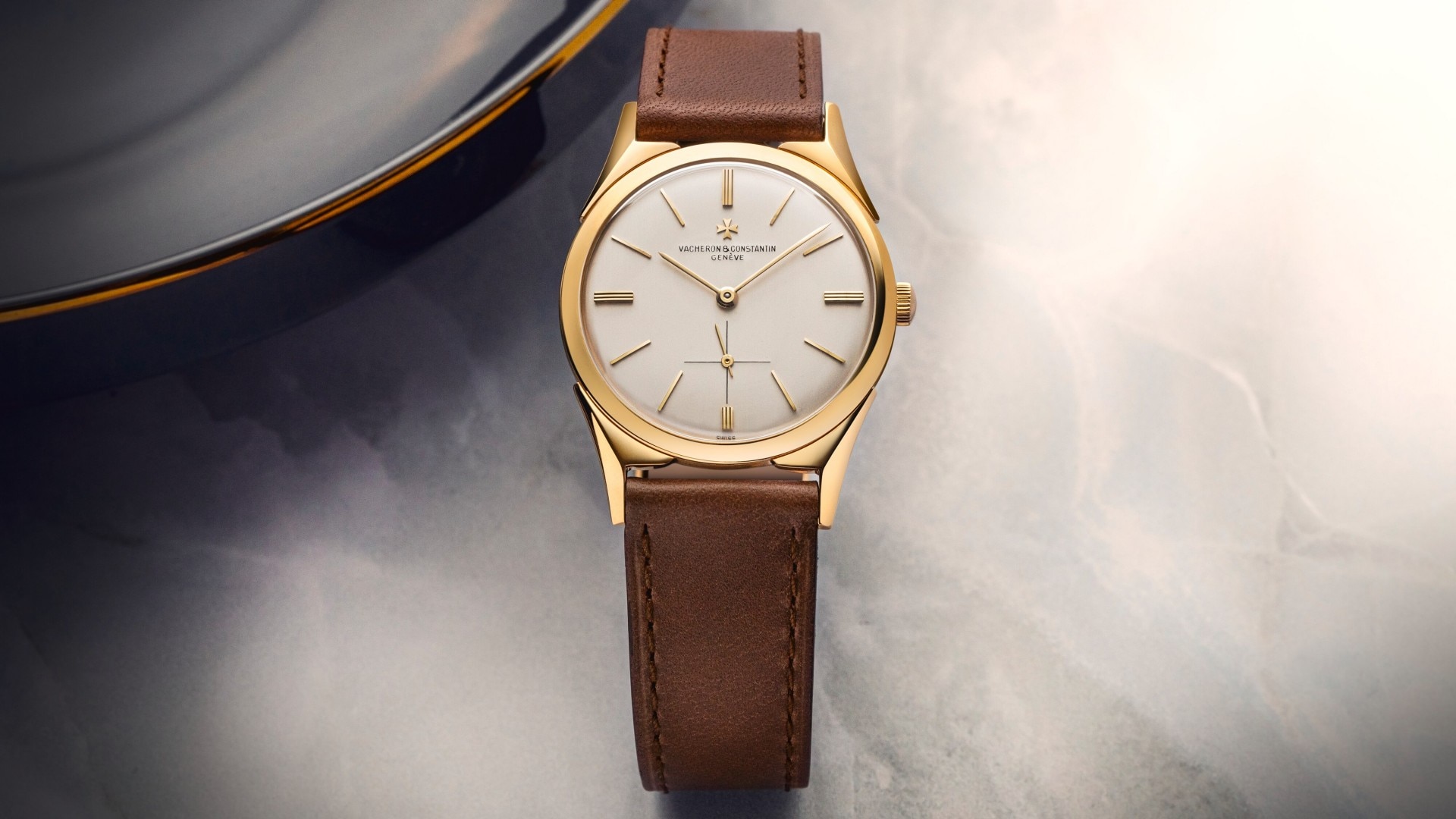 Elegant wristwatch featuring a gold bezel, gold hands, a light crystal, and an ochre leather strap.