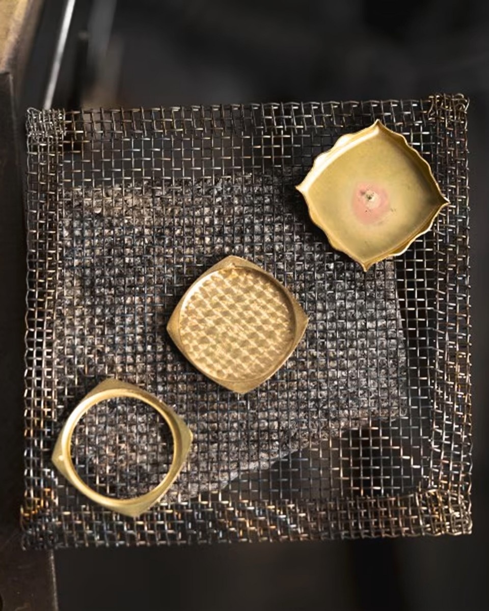 Selection of small watch components and golden elements placed on a metal mesh tray.